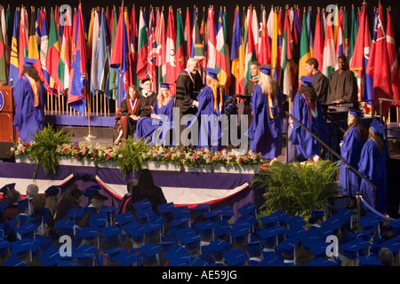 Gli studenti universitari a piedi attraverso una fase di ricevere i loro diplomi in una università cerimonia di laurea Foto Stock