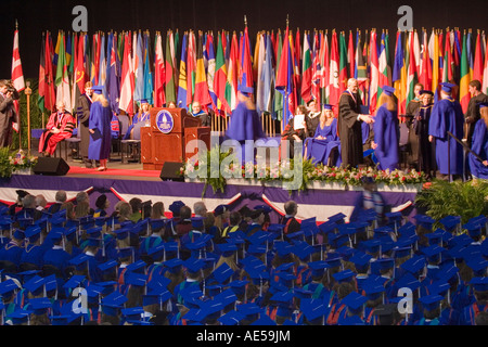 Gli studenti universitari a piedi attraverso una fase di ricevere i loro diplomi in una università cerimonia di laurea Foto Stock
