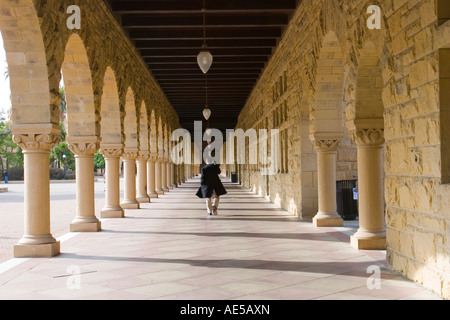 Il Portico in principali Quad della Stanford University con un uomo a camminare lungo le arcate in pietra arenaria e colonne Stanford in California Foto Stock