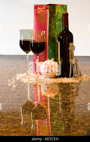Dono del vino rosso Bottiglia con due bicchieri accanto alla festa di Natale ornamento e apribottiglie sul banco in granito Foto Stock