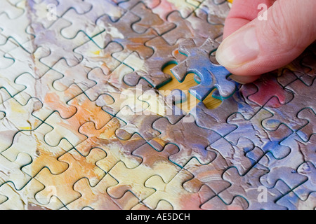 Puzzle di pezzi collegati insieme con la mano la messa in l'ultimo pezzo mancante Foto Stock