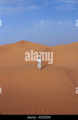 Tourist salendo su una duna di sabbia nel deserto del Sahara in Marocco Foto Stock