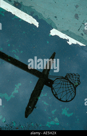 Lavagna Basketball hoop e net riflettendo nella pozza di rundown schoolyard pallacanestro Foto Stock