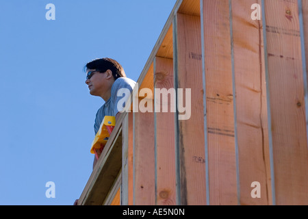 Uomo che guarda fuori dalla parte superiore della parete incorniciato a sognare la nuova casa che stanno costruendo Foto Stock