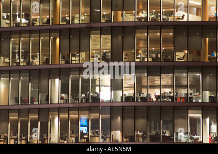 Diversi piani di costruzione di ufficio visto dall'esterno attraverso finestre di vetro di notte Foto Stock
