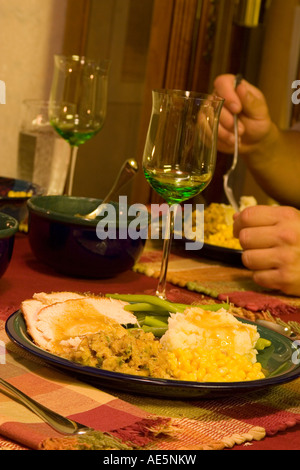 Sedersi a tavola a mangiare farine di Ringraziamento con la Turchia purè di patate con sugo di carne ripieno e i fagiolini verdi Foto Stock