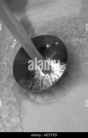 Acqua di rubinetto versando giù PLU FORO IN BIANCO il lavandino del bagno Foto Stock