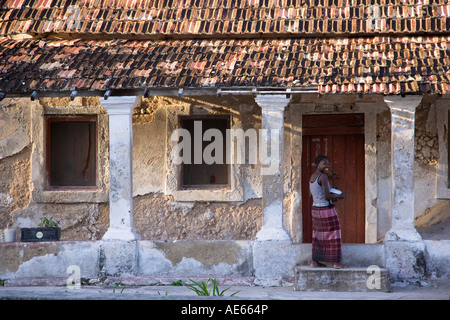 Una donna di fronte a una vecchia villa portoghese su ibo isola parte dell'Arcipelago Quirimbas Mozambico Foto Stock