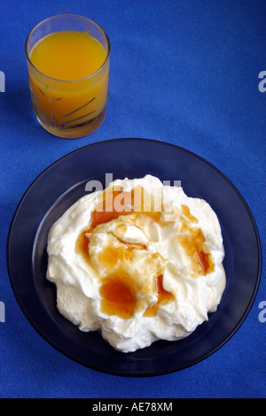 Una tazza di delizioso yogurt greco con miele e un bicchiere di succo d'arancia fresco Foto Stock