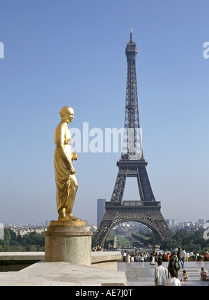 Uno degli otto dorata oro statue a Place du Trocadéro sulla terrazza dei diritti dell'uomo con la Torre Eiffel struttura punto di riferimento al di là di Parigi Francia UE Foto Stock