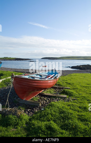 Dh Stenness ESHA NESS SHETLAND Spiaggiata fishermans rosso barca spiaggia della baia e l'isola di Stenness Foto Stock