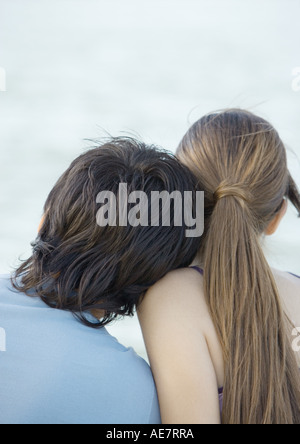 Un giovane uomo pendente sulla testa della ragazza, spalla, vista posteriore Foto Stock