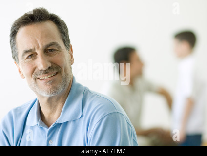 Uomo maturo, ritratto, figlio e nipote in background Foto Stock