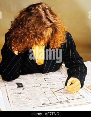 Giovane donna lettura immobiliare di annunci pubblicitari su un giornale, Germania Foto Stock