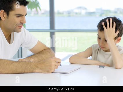 Ragazzo facendo i compiti con l'opera del padre, ritagliato Foto Stock