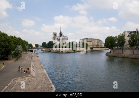 Un gruppo di ciclisti in pausa sulla riva sinistra con la cattedrale di Notre Dame e il Pont de La Tournelle ponte sopra il fiume Senna a Parigi Foto Stock