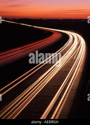 Tramonto al di là del veicolo sentieri di luce su tre corsie a doppia carreggiata autostrada A12 trunk road in Essex England Regno Unito il crepuscolo della sera Rush Hour Foto Stock