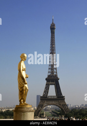 Uno degli otto dorata oro statue a Place du Trocadéro sulla terrazza dei diritti dell'uomo con la Torre Eiffel struttura punto di riferimento al di là di Parigi Francia UE Foto Stock