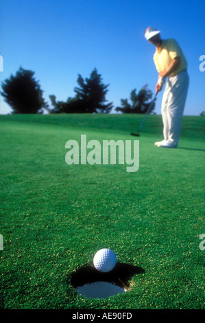 L'uomo giocando a golf con palla circa a cadere nel foro Modello rilasciato image Foto Stock