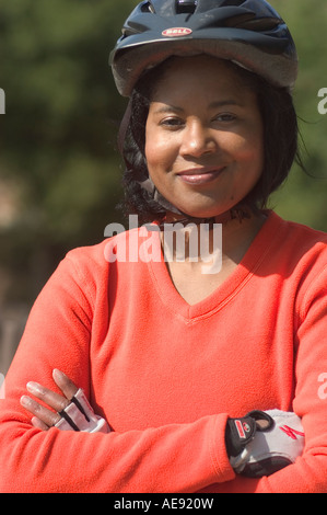 Un giovane 20 qualcosa di African American donna esercizio al di fuori del vestito di un casco protettivo e luminose maglietta arancione. Foto Stock