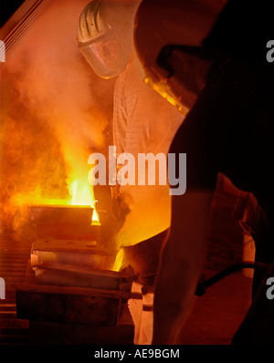 Fonderia di bronzo uomini colata di bronzo fuso in stampi in smokey firey fonderia Foto Stock