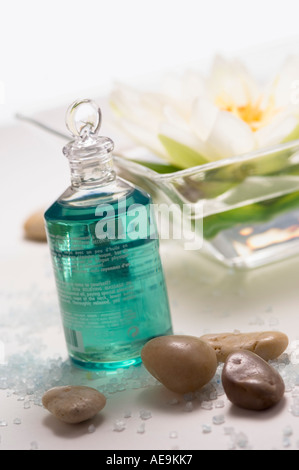 Olio essenziale bottiglia, peebles e acqua giglio fiore, close-up Foto Stock