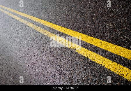 Due giallo linee barriera verniciato per asfalto Foto Stock