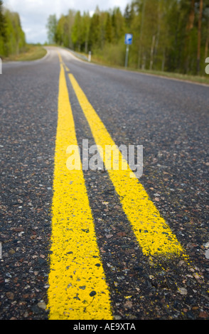 Close-up di due dipinte di giallo linee barriera su asfalto su una tranquilla strada di campagna , Finlandia Foto Stock