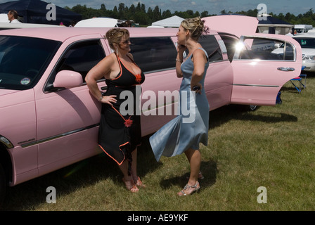 Donne bianche della classe operaia si vestivano, i migliori vestiti estivi limousine rosa allungata. Limos ha parcheggiato sulla Heath, Royal Ascot 2006 2000s UK HOMER SYKES Foto Stock