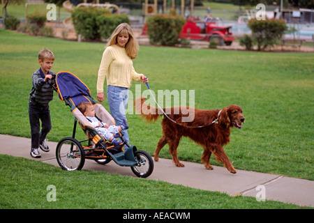 Una giovane donna prende i due figli e il cane per una passeggiata MR Foto Stock