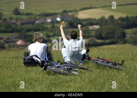 Un maschio femmina ciclista sedersi e prendere in vista rurale guardando oltre il Sussex Downs Devil's Dyke EAST SUSSEX Foto Stock