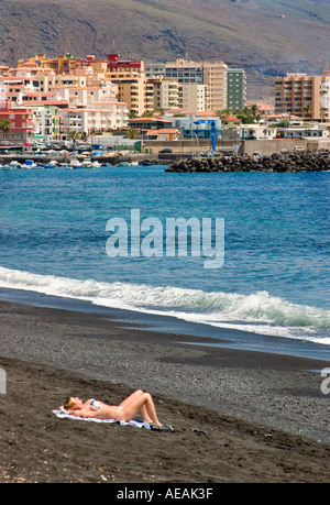 La donna a prendere il sole sulla spiaggia vulcanica Candelaria Tenerife Canarie Spagna Foto Stock