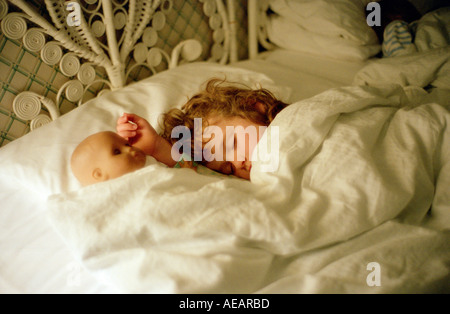 Un bambino di sei anni ragazza dorme pacificamente con la sua bambola accanto a lei sul cuscino Inghilterra Foto Stock