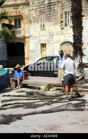 I pescatori con le loro reti sulla banchina del porto di Marsaxlokk. MALTA EUROPA Foto Stock