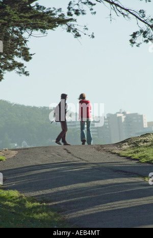 Due persone che camminano nel parco lungo il percorso con la città nella distanza, CALIFORNIA, STATI UNITI D'AMERICA Foto Stock
