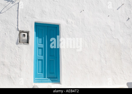 Greco finestra turchese contro un entro un bianco lavato gli edifici si trovano comunemente sulle isole greche Foto Stock