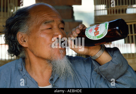 Commerciante di mercato di vendita di gabbie di uccelli di bere una birra durante la sua pausa pranzo a Pechino Pechino CINA Foto Stock