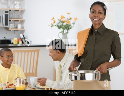 Donna africana che serve la prima colazione al marito e figlio Foto Stock