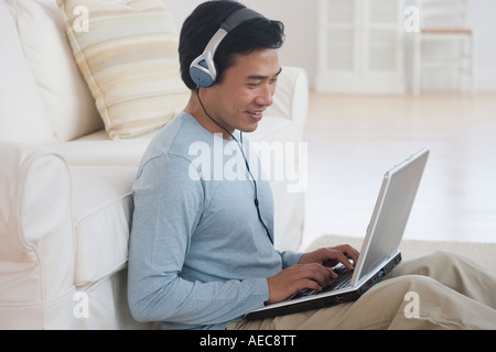 Uomo asiatico utilizzando computer portatile con cuffie Foto Stock