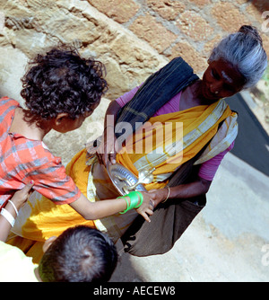 Una vecchia signora vestita di saree accetta bracci da due bambini, Kerala, India Foto Stock