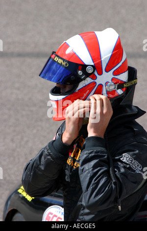 Race Driver facendo il suo casco prima dell'inizio di una corsa Foto Stock