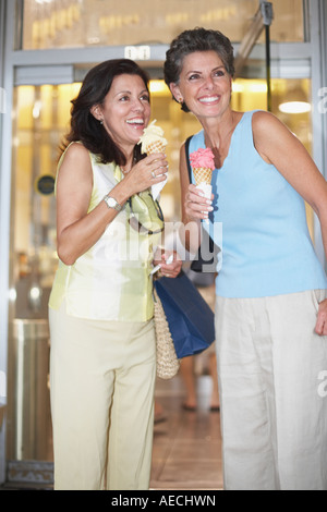 Due donne ispaniche mangiare coni gelato Foto Stock