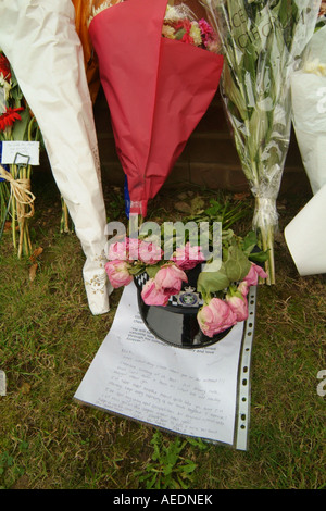 Un poliziotto del casco, omaggi floreali e un tributo scritta da uno dei suoi colleghi a sinistra in prossimità di un incidente mortale Foto Stock
