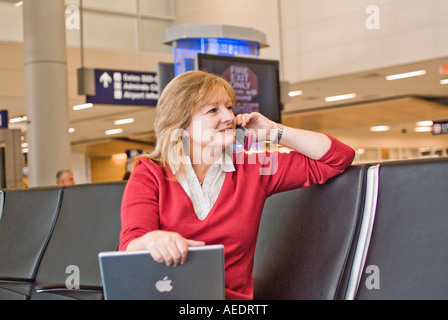 Attraente seduta femminile nel terminale di linea aerea con computer portatile Foto Stock