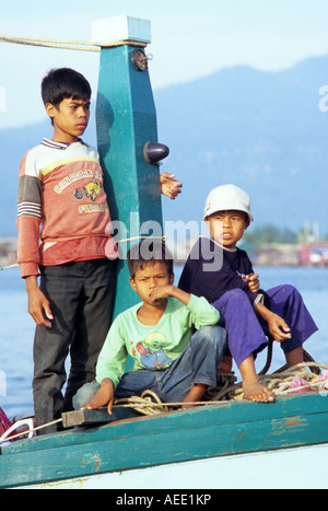 Tre giovani ragazzi Cham seduto su una barca da pesca sul fiume Sanke, Kampot, Cambogia Foto Stock