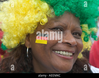 Una femmina di fan del calcio brasiliano squadra indossa una parrucca nei suoi colori nazionali e ha una piccola bandiera tedesca incollata sulla sua guancia Foto Stock