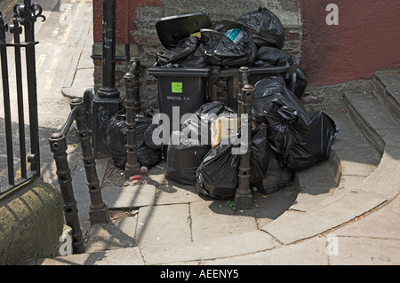 Traboccante nero sacchi per immondizia e wheely bin in attesa per la raccolta e per il percorso di blocco Bristol Inghilterra Foto Stock