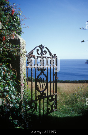 Gorran Haven Cornwall Inghilterra REGNO UNITO vista attraverso aprire cancellata in ferro battuto sul granito gatepost con vista della baia di Veryan mare blu Foto Stock