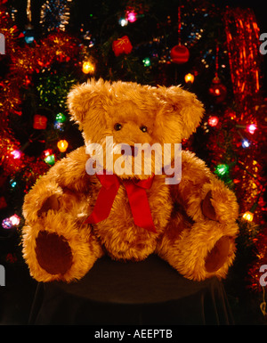 Orsacchiotto di peluche bambola seduta di fronte a decorazioni natalizie e luci colorate Foto Stock