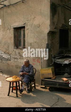 Vecchia donna pela verdure in un angolo di strada in un area a causa di demolizioni, Shanghai Foto Stock